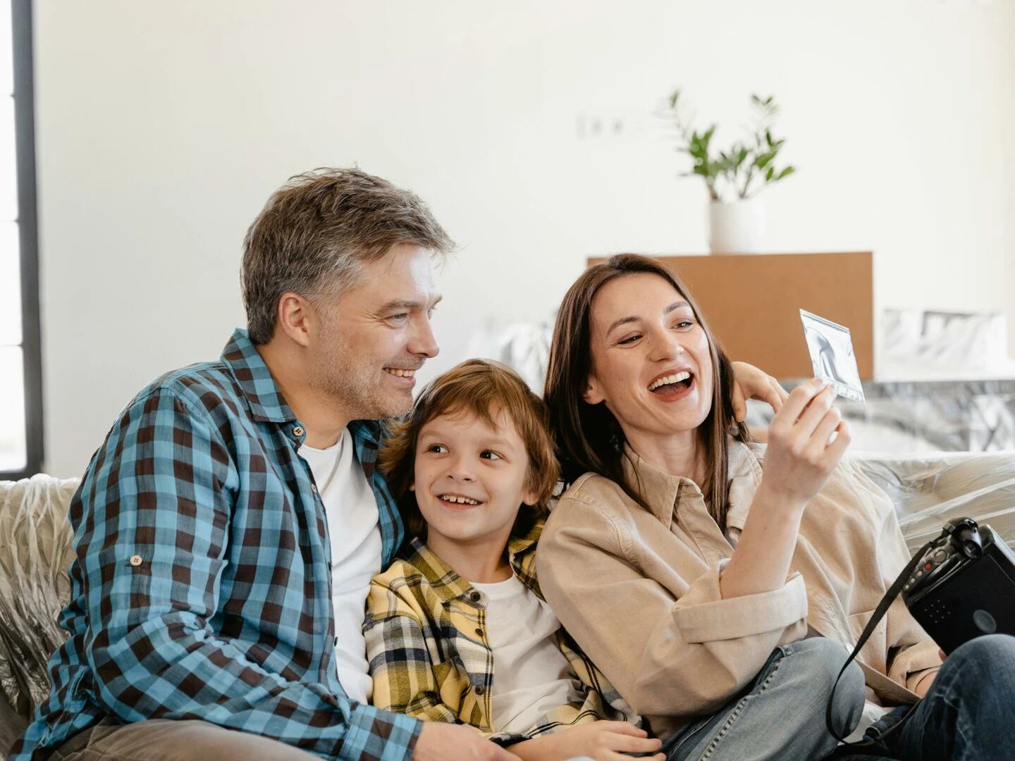 a cheerful family enjoys time together on a couch surrounded by moving boxes in their new home