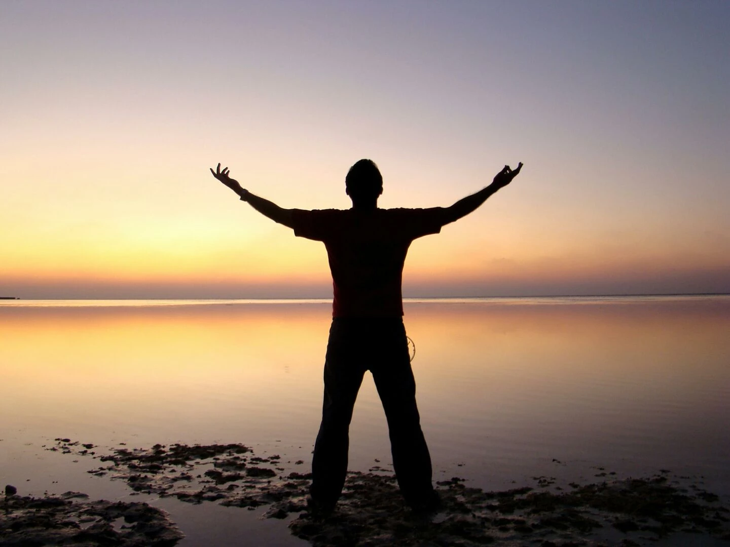 a person joyfully embracing the sunrise over a calm ocean symbolizing freedom and solitude