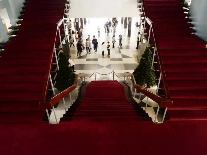 a red carpeted staircase with people walking up it