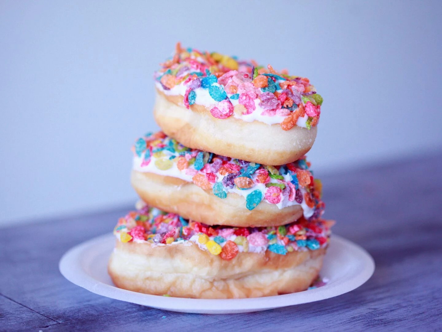 a stack of doughnuts covered in colorful fruity pebbles on a plate