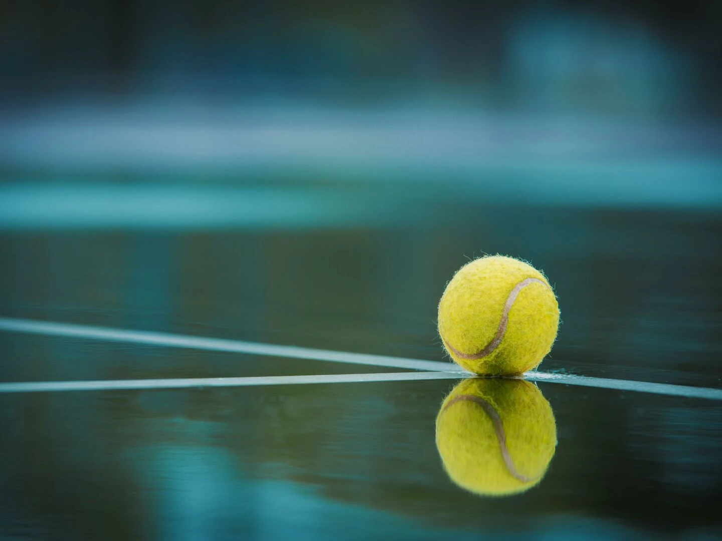 a tennis ball sits on a wet court with its reflection visible capturing a serene sports moment