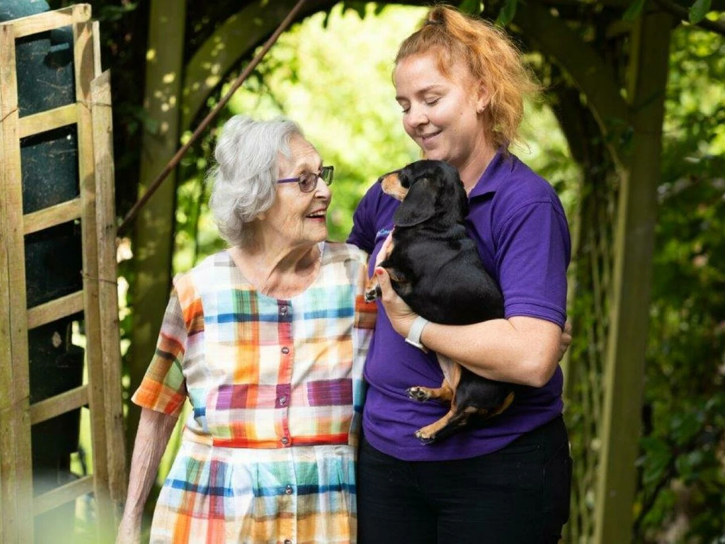 ann in her garden with her dog amei and carer jody