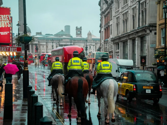 back view of police officers on horseback on a busy street in london england uk