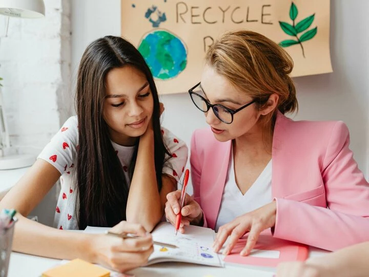 Teacher assists student with homework, promoting educational bonding.