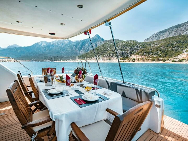 Elegant dining setup on a yacht overlooking Antalya's scenic coast in Türkiye.