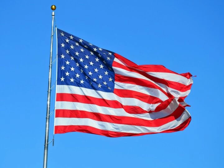 Majestic American flag waving against a bright blue sky, symbolizing freedom and patriotism.