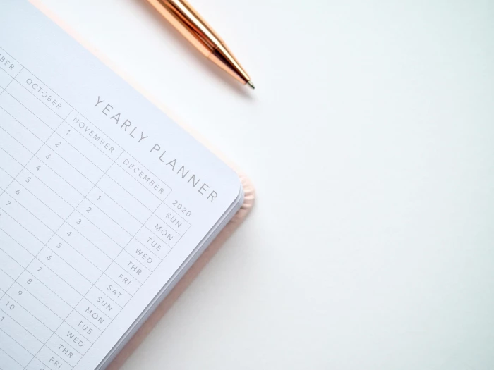 closeup photo of yearly planner beside a pen
