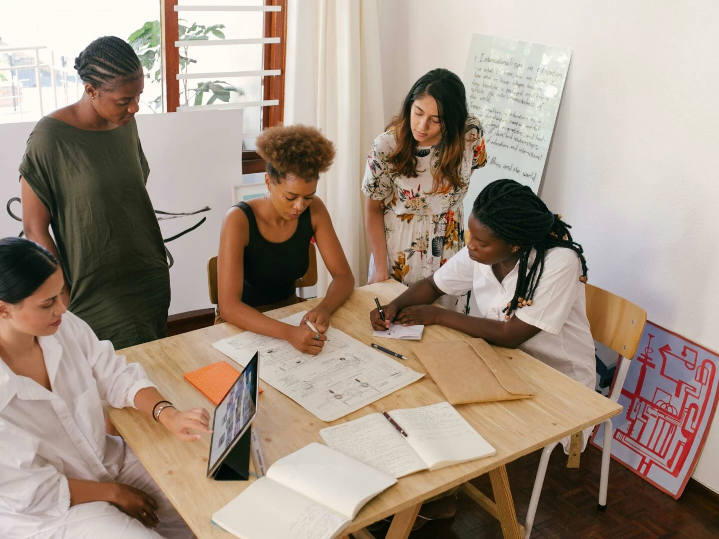 diverse team collaborates on a project using digital and paper resources in a bright office