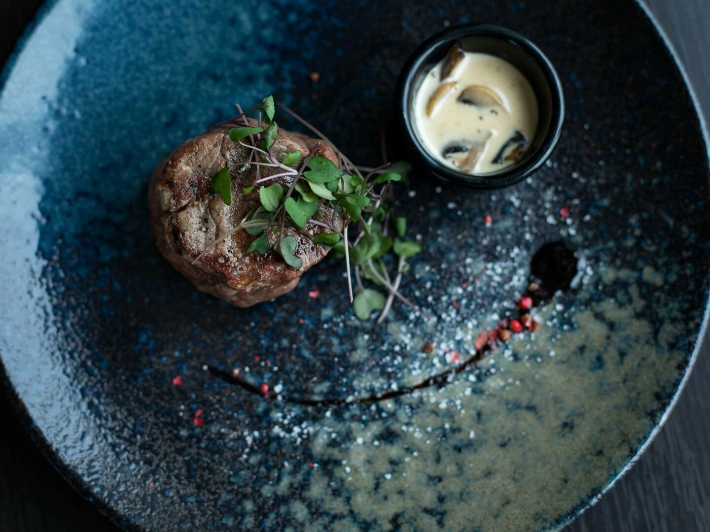 elegant plated steak dish garnished with microgreens and served with creamy mushroom sauce