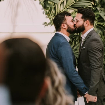 menwearingsuitkissinginfrontofpeople3491999