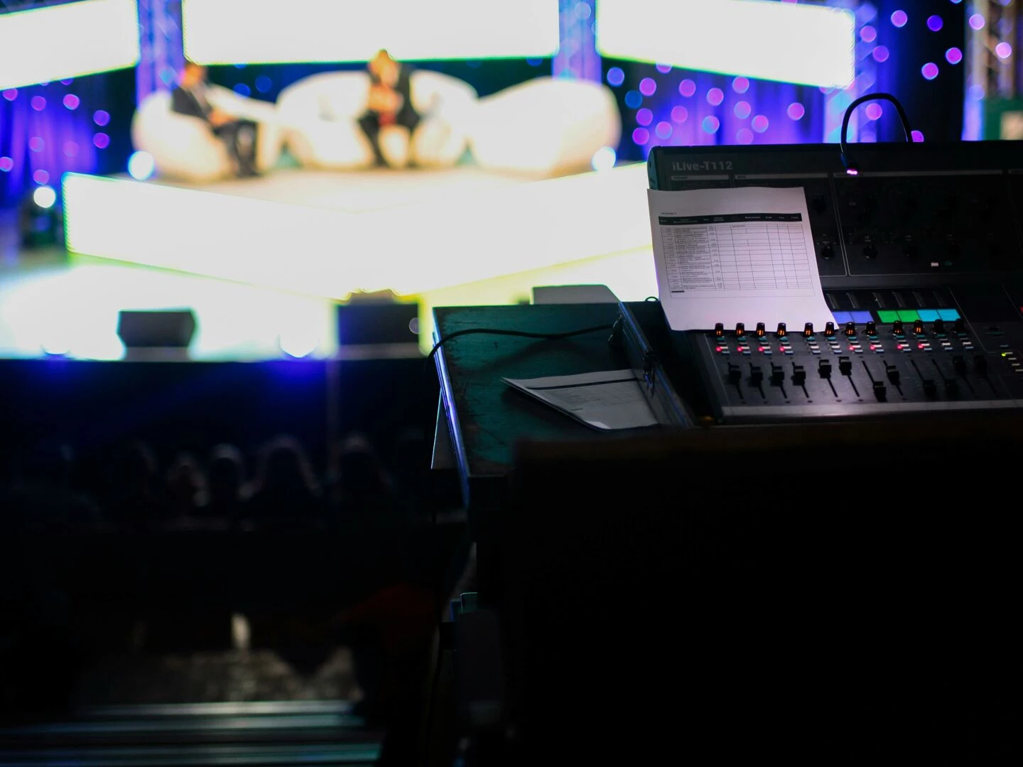 sound console in a studio setting for a live event with blurred audience view
