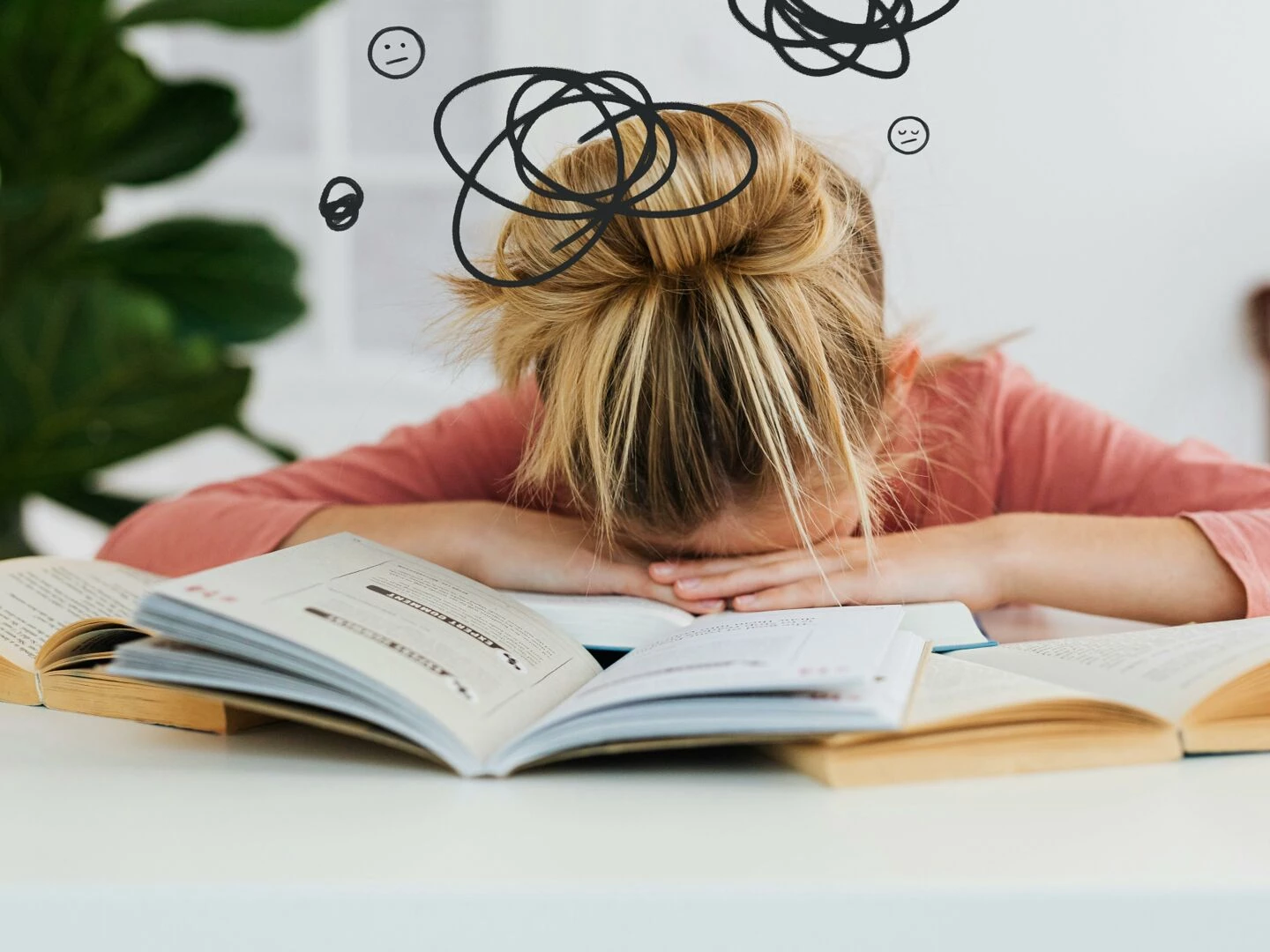 young woman asleep over books at desk conveying stress and mental overload